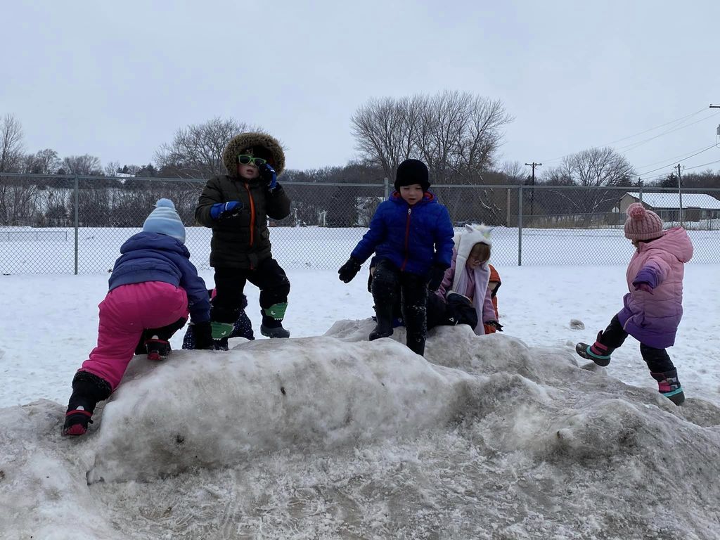 Eight children climbing a hill of snow