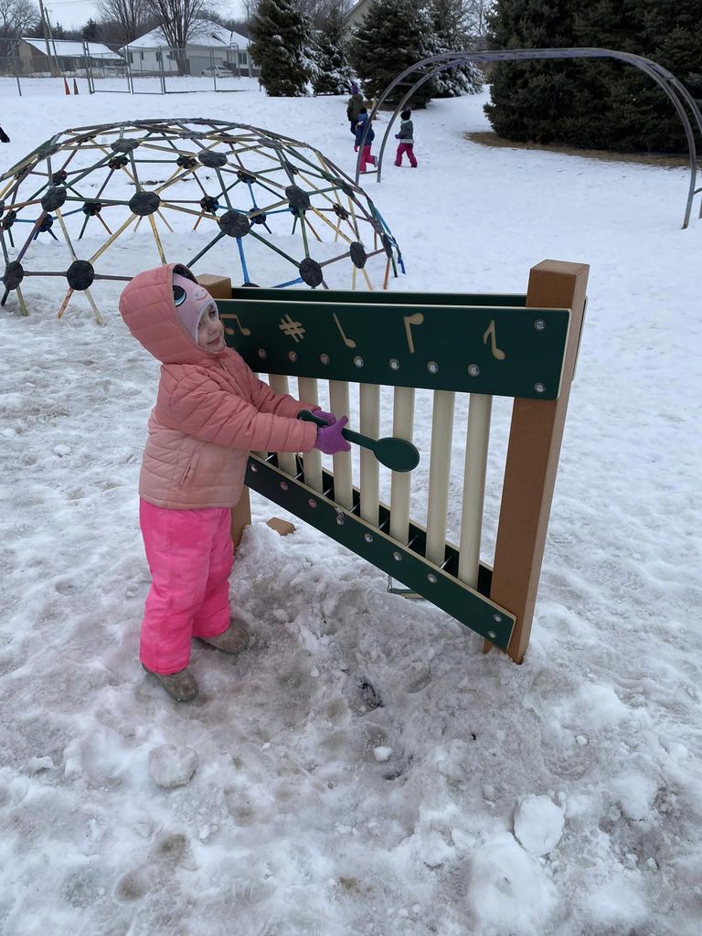 Child playing with playground equipment in the snow